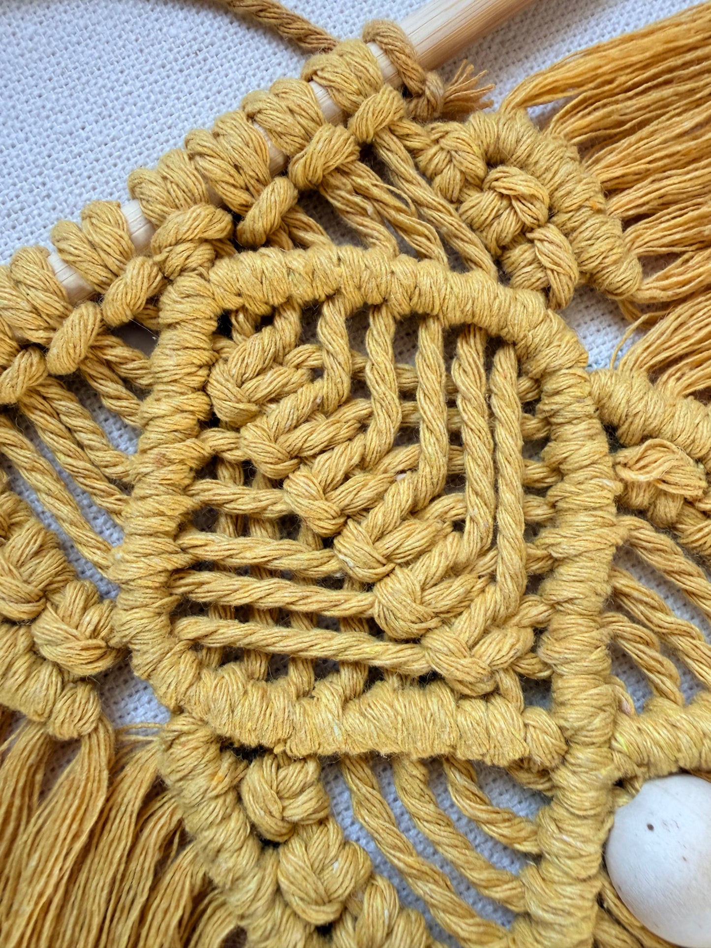 Close-up of intricate knots on a handmade mustard macrame leaf wall hanging