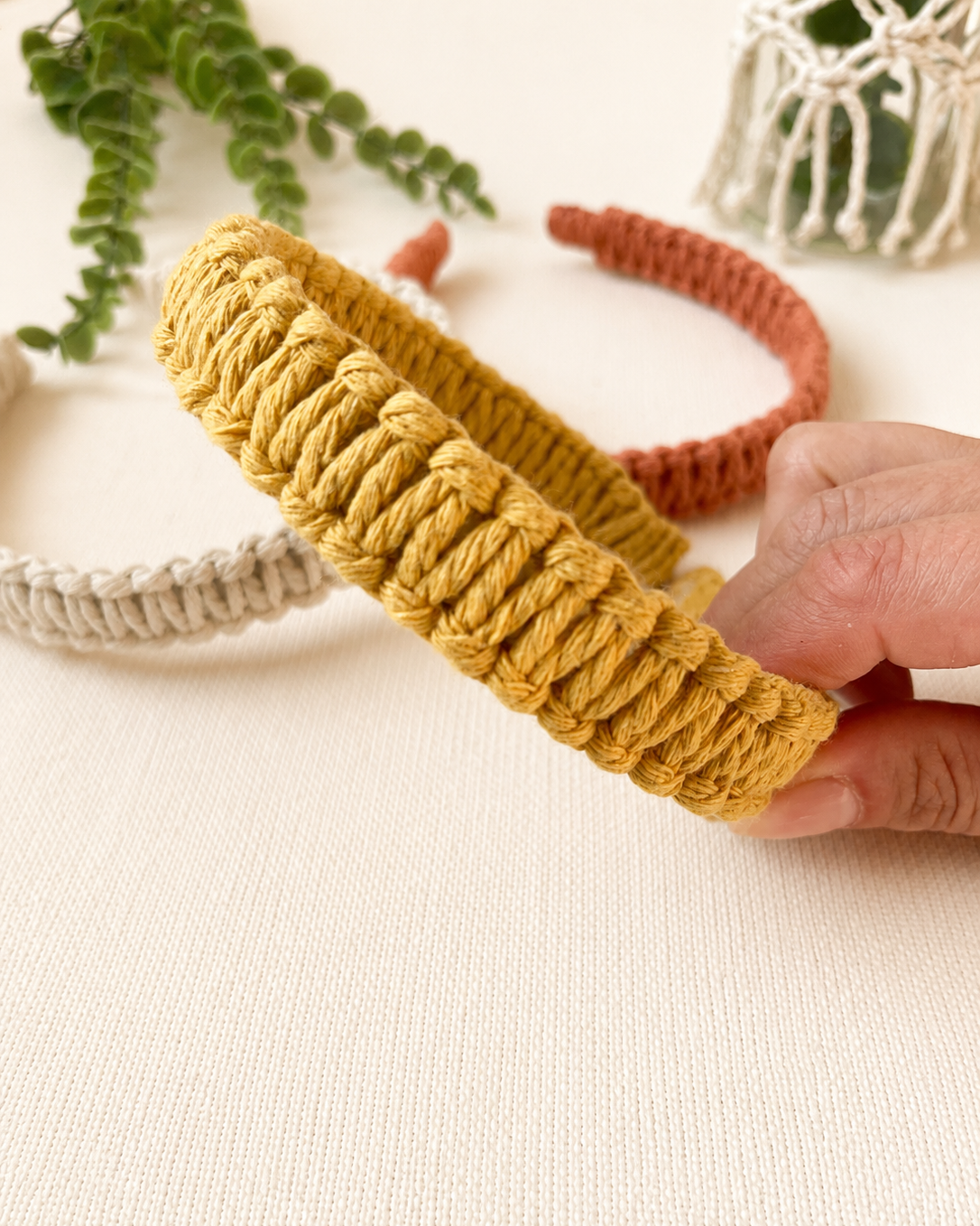 Close-up of a handmade mustard macrame square knot headband showing the textured knot pattern.