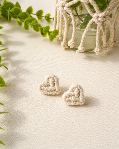 Off-white handmade macramé heart stud earrings on a neutral fabric background