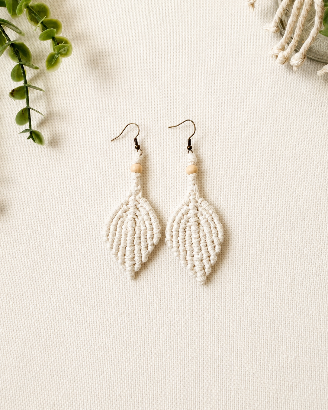 Handmade off white macrame leaf earrings with wooden bead detail and antique bronze hooks.