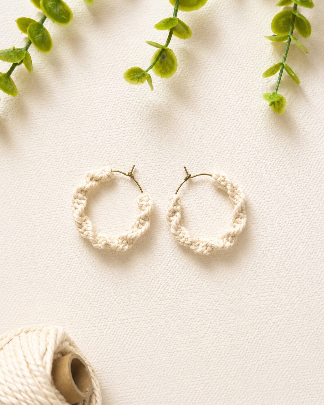 Off-white handmade macramé spiral hoop earrings with lightweight hoop design.
