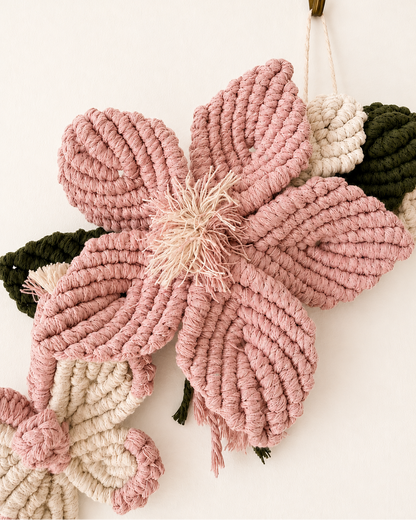 Close-up of handmade blush pink macrame flower with green leaves