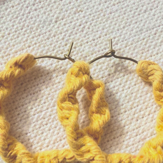 Video showing handmade macramé spiral hoop earrings from different angles.