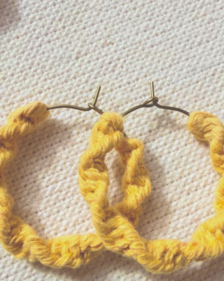 Video showing handmade macramé spiral hoop earrings from different angles.