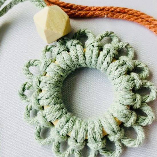 Close-up video showing the handmade sage green macrame flower car diffuser with natural wooden bead and textured cotton knots.
