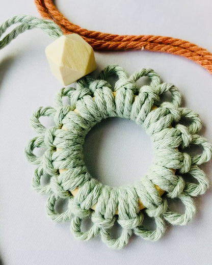 Close-up video showing the handmade sage green macrame flower car diffuser with natural wooden bead and textured cotton knots.