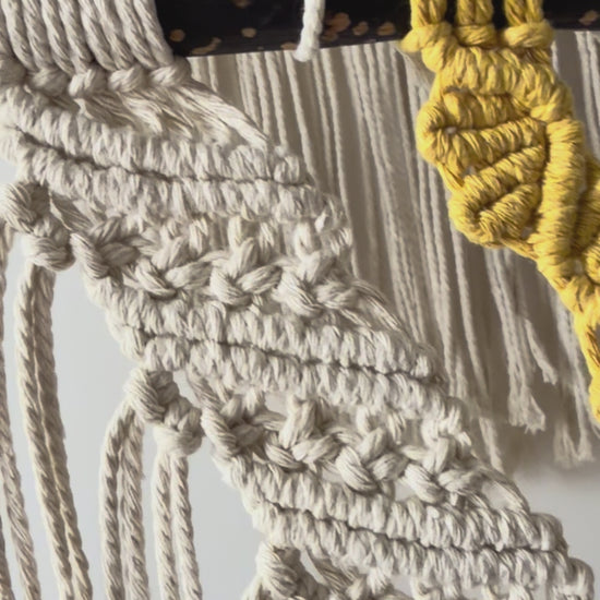 Close-up side view of the handmade macrame wall hanging showcasing intricate knotwork and layered cotton textures.