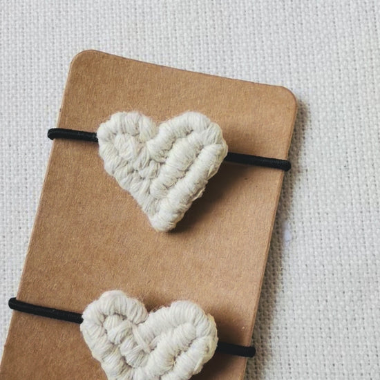 Video showing handmade macrame heart hair ties from different angles and close-up details.