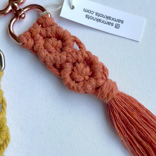 Video showcasing handmade macrame diamond keychains in multiple colours with tassels and metal clasps.