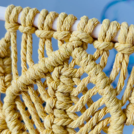 Detail of cotton cord knotwork on a handmade mustard macrame wall hanging