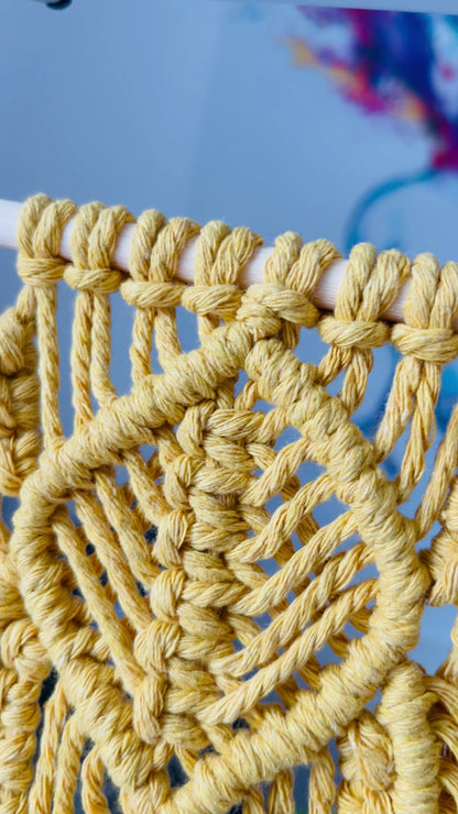 Detail of cotton cord knotwork on a handmade mustard macrame wall hanging