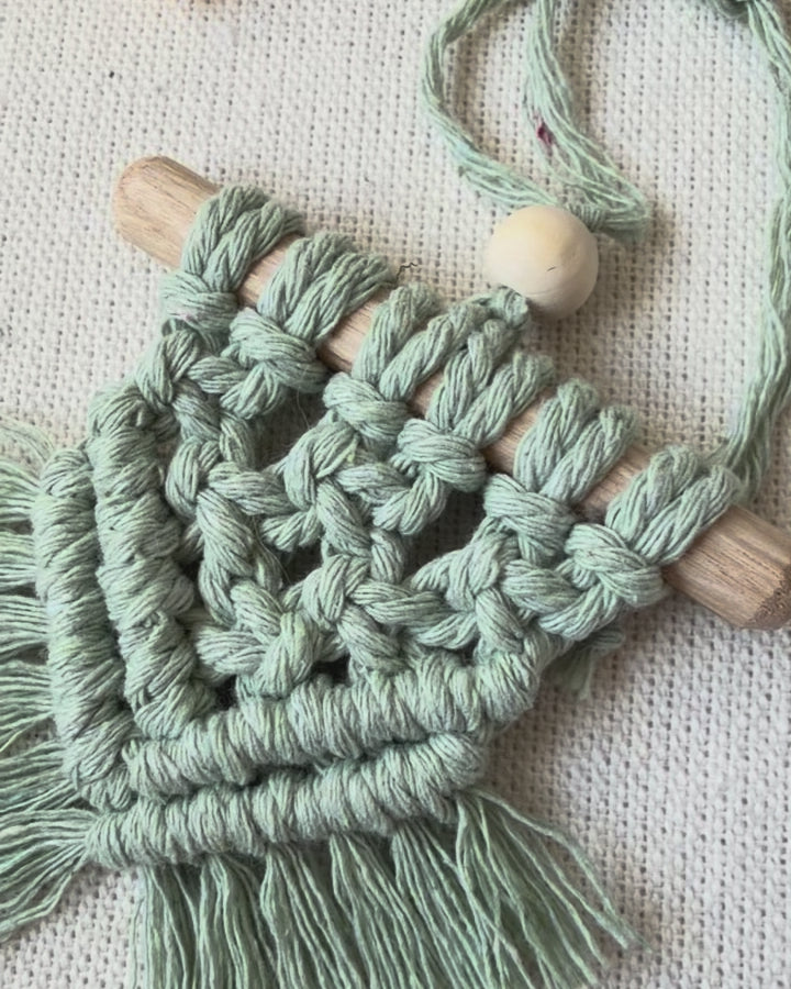 Video showcasing boho macramé car charms in multiple colours including off white, mustard, mint green and light brown, handmade from cotton cord.