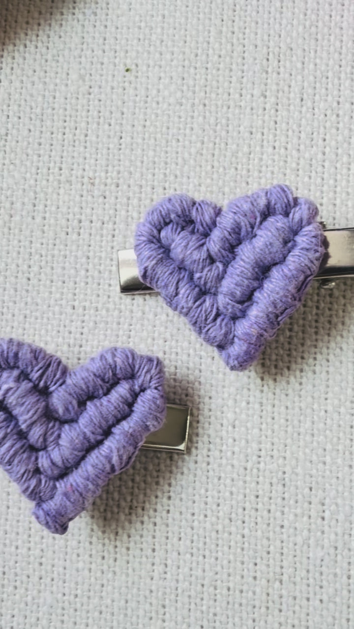 Video showing handmade macrame heart hair clips in natural, blush pink, lilac and fuchsia colours.