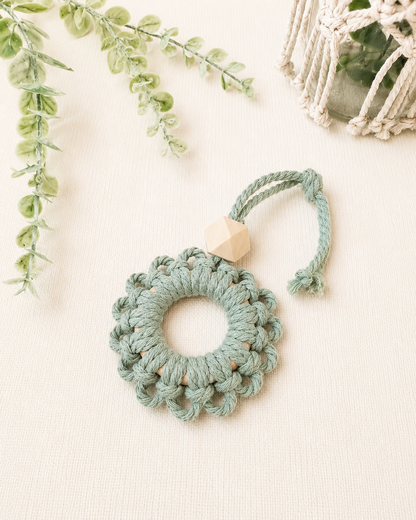 Handmade sage green macrame flower car diffuser with a natural wooden bead for essential oils and car décor.