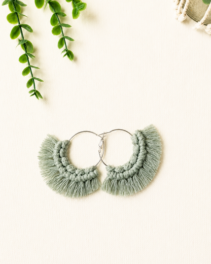 Handmade sage green macrame fringe hoop earrings with stainless steel hoops.