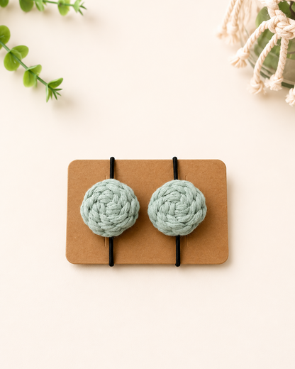 Sage green handmade macrame cotton hair ties with black elastic bands.