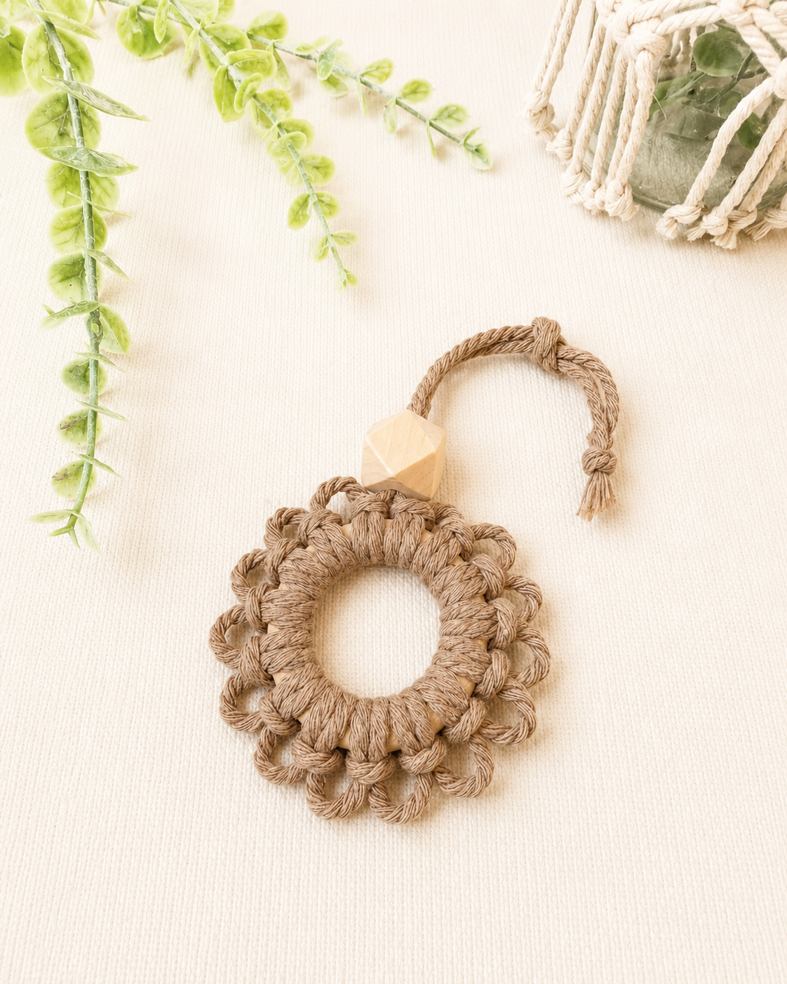Handmade taupe macrame flower car diffuser with a natural wooden bead for essential oils and neutral car décor.