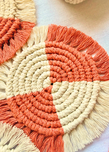 Handmade terracotta and off white macramé coaster flat lay on soft linen fabric with boho styling details.