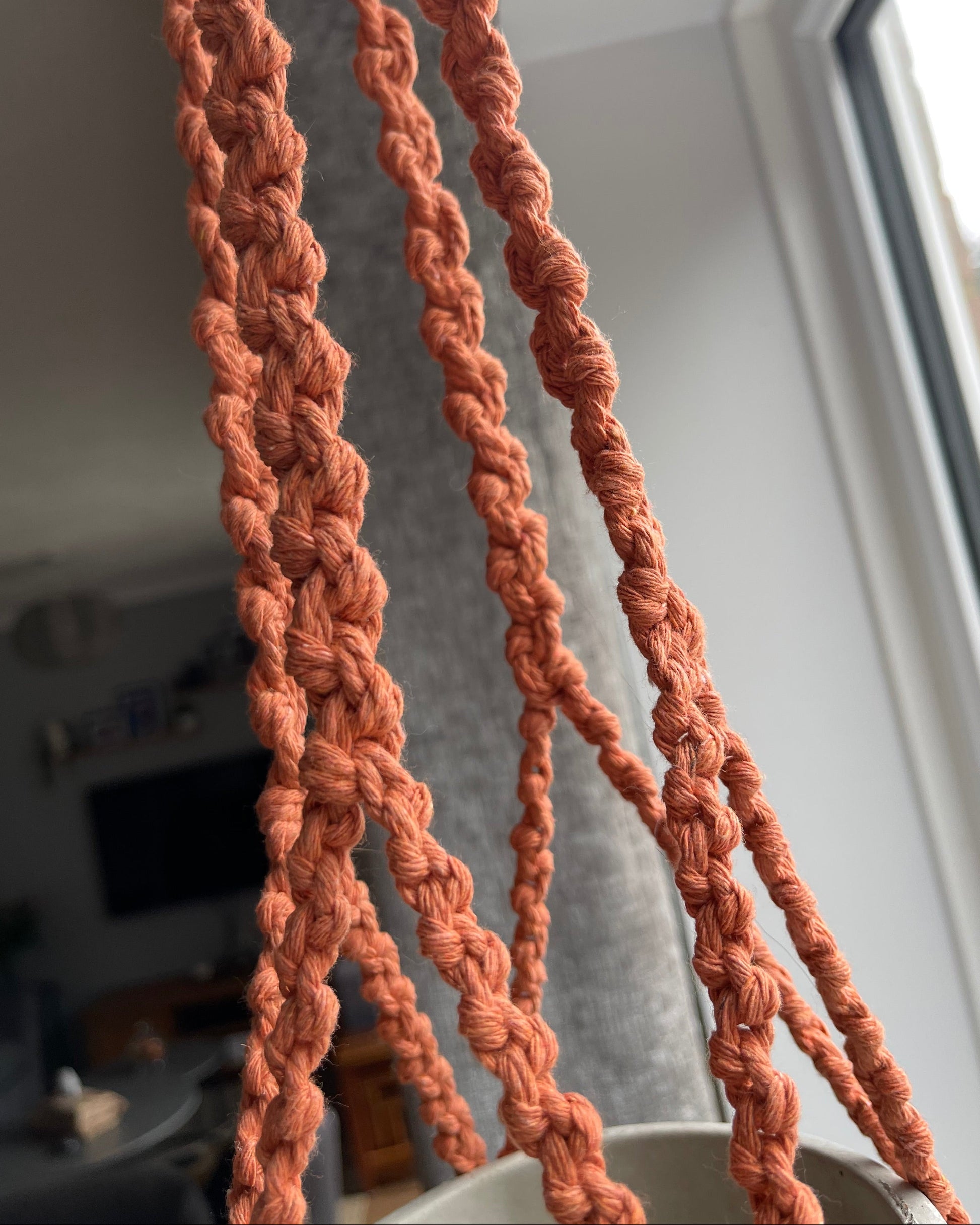 Detailed view of handmade half hitch knots in a terracotta macrame plant hanger, showing the knot texture and craftsmanship.