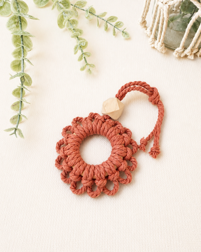 Handmade terracotta macrame flower car diffuser with a natural wooden bead for essential oils and boho car décor.