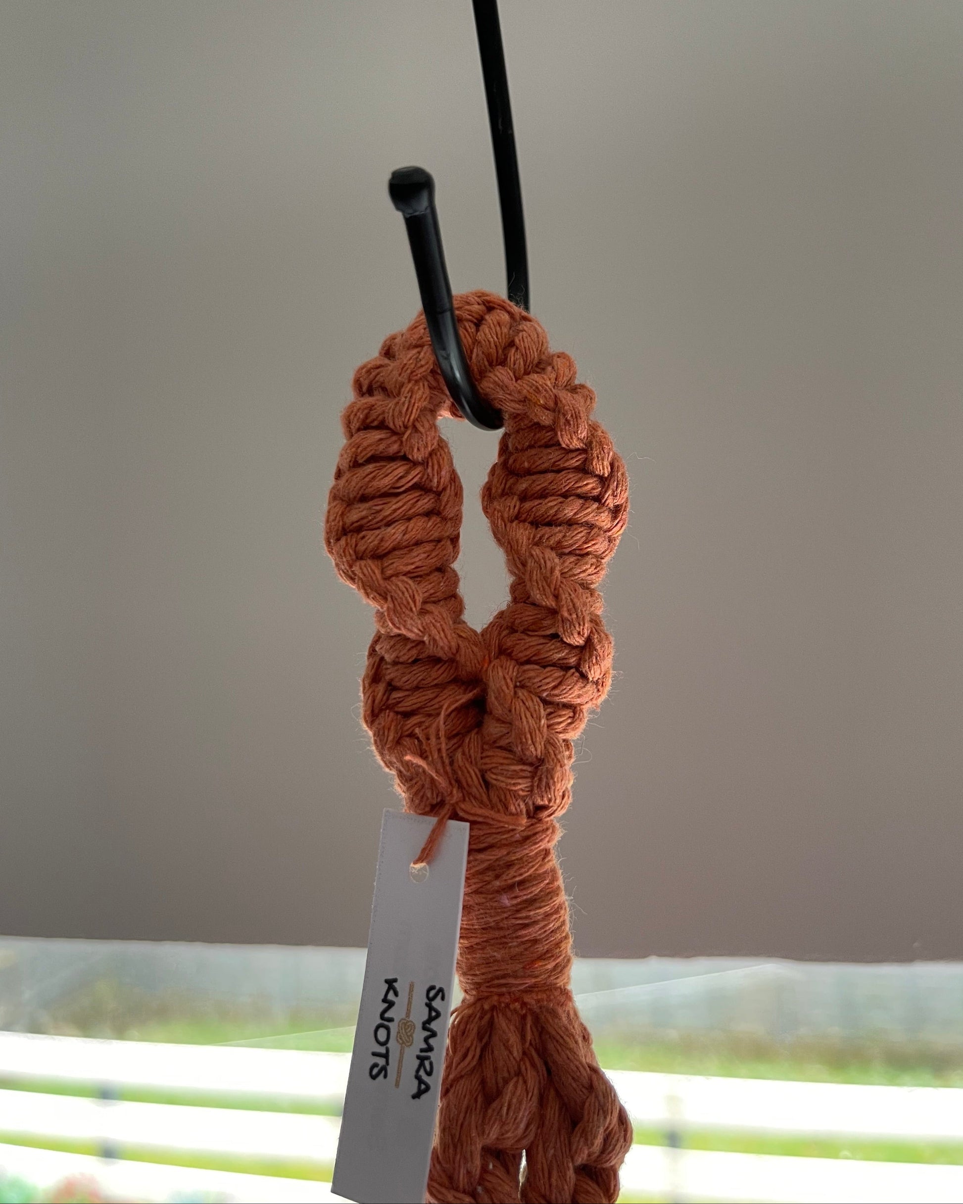 Close-up of the top hanging loop and finishing knots of a terracotta handmade macrame plant hanger.