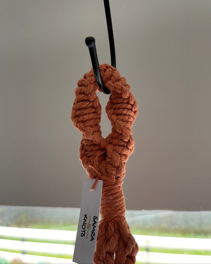 Close-up of the top hanging loop and finishing knots of a terracotta handmade macrame plant hanger.
