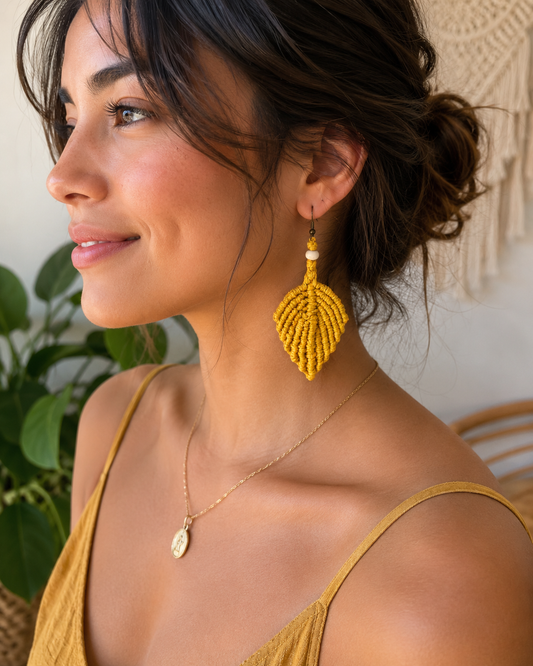 Woman wearing handmade mustard yellow macrame leaf earrings with wooden bead detail.